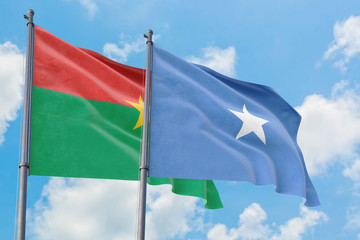 Somalia and Burkina Faso flags waving in the wind against white cloudy blue sky together. Diplomacy concept, international relations.