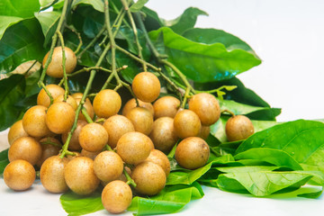 Some wampee and green leaves on a white background.