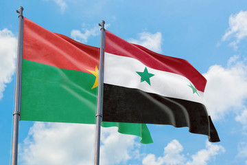 Syria and Burkina Faso flags waving in the wind against white cloudy blue sky together. Diplomacy concept, international relations.