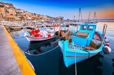 Obraz premium Seaside city of Kavala in Greece. Coloful evening scene, eastern Macedonia, Europe. Greek fishing boats. View on dock for boats and yachts in a beautiful spring evening.