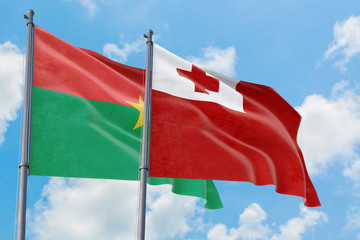 Tonga and Burkina Faso flags waving in the wind against white cloudy blue sky together. Diplomacy concept, international relations.