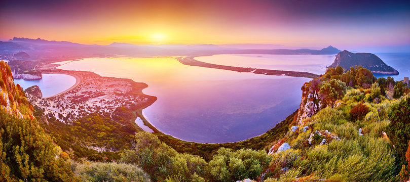 Amazing sunrise view with multicolored clouds from Navarino Castle. Romantic sunset on Voidokilia beach, Ionian Sea, Pilos town location, Greece, Europe. View of the ocean through the rocky shore