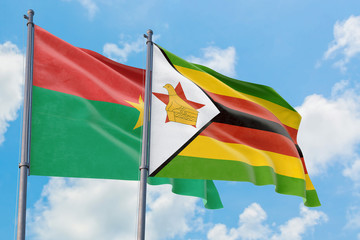 Zimbabwe and Burkina Faso flags waving in the wind against white cloudy blue sky together. Diplomacy concept, international relations.