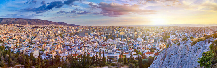 An evening cityscape of many buildings of Athens City, Greece. View from Filopappou Hill or Hill of the Muses. Colorful spring landscape. Urban skyscraper skyline rooftop view at night.