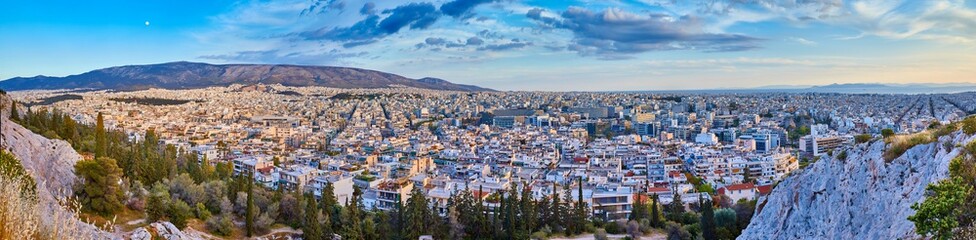 An evening cityscape of many buildings of Athens City, Greece. View from Filopappou Hill or Hill of the Muses. Colorful spring landscape. Urban skyscraper skyline rooftop view at night.