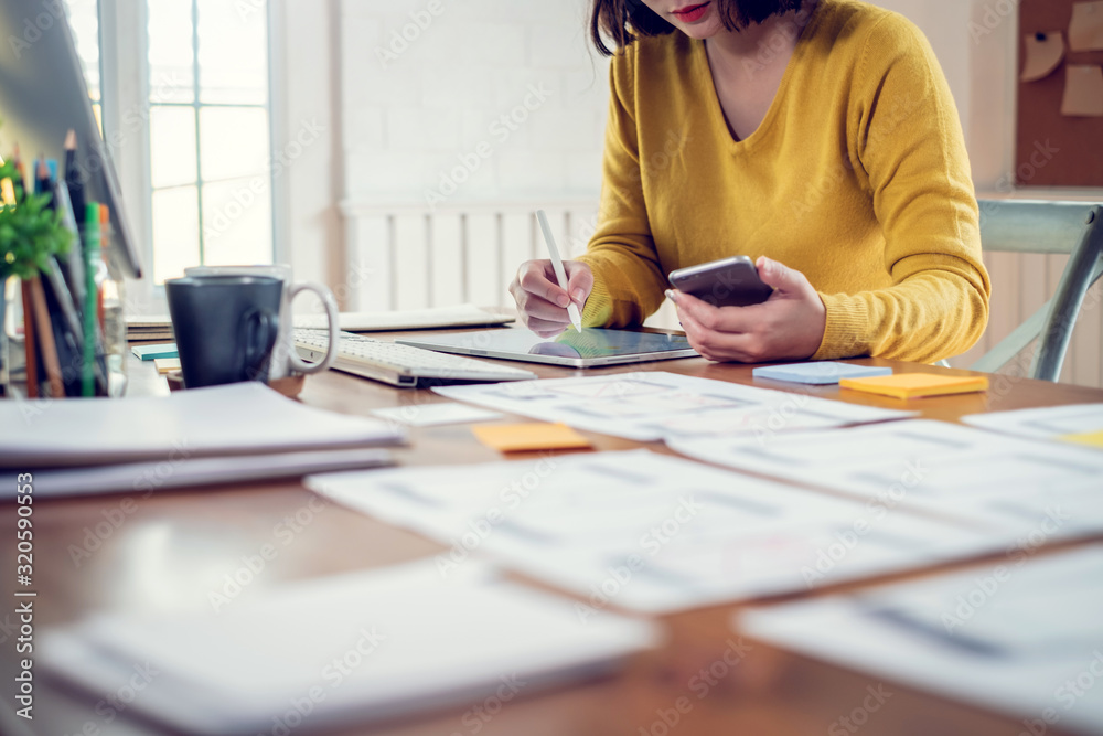 Wall mural designer woman drawing a website outline and website ux app development on mobile phone.