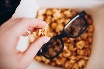 woman hand takes from a box of sweet popcorn  in a movie theater cinema rest entertainment