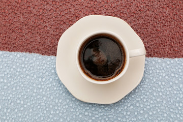 Close-up - a cup of coffee on a red-blue background.
