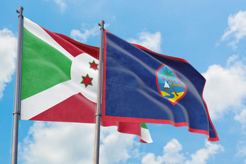 Guam and Burundi flags waving in the wind against white cloudy blue sky together. Diplomacy concept, international relations.