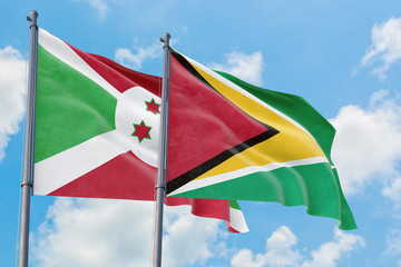 Guyana and Burundi flags waving in the wind against white cloudy blue sky together. Diplomacy concept, international relations.