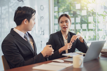 Two young asian  discussing about the project in the office. Happy colleagues in modern office.