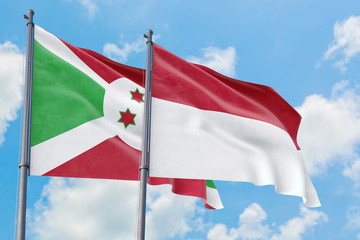 Indonesia and Burundi flags waving in the wind against white cloudy blue sky together. Diplomacy concept, international relations.
