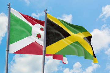 Jamaica and Burundi flags waving in the wind against white cloudy blue sky together. Diplomacy concept, international relations.