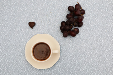 Close-up - a cup of coffee, next to two heart-shaped chocolates.
