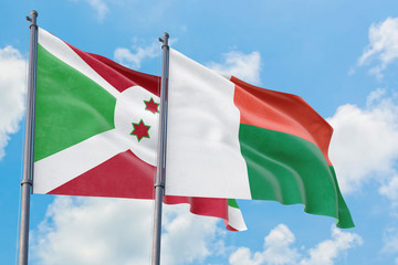 Madagascar and Burundi flags waving in the wind against white cloudy blue sky together. Diplomacy concept, international relations.