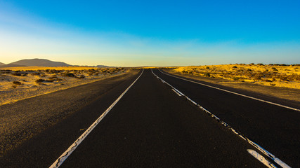 Fototapeta na wymiar carretera en el desierto en verano con cielo azul