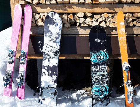 Set of alpine skis and splitboards leaning on wooden wall. Sport equipment for ski touring