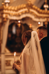 Orthodox church, sacrament of a wedding ceremony, couple, priest, golden church interior, candles,...