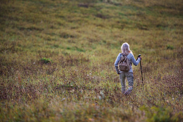 Rear view of senior woman on walk outdoors in nature. Copy space.