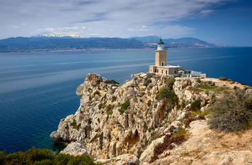 Fototapeta na wymiar Melagkavi Lighthouse also known as Cape Ireon Light perching high on a headland overlooking eastern Gulf of Corinth, Greece. Bright sunny view of spring seascape, Cape Melagavi.