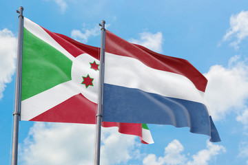 Netherlands and Burundi flags waving in the wind against white cloudy blue sky together. Diplomacy concept, international relations.