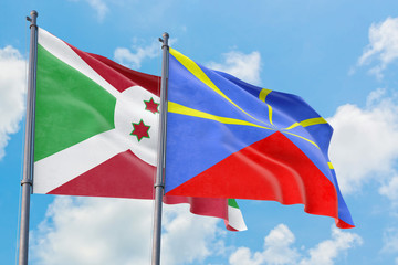 Reunion and Burundi flags waving in the wind against white cloudy blue sky together. Diplomacy concept, international relations.