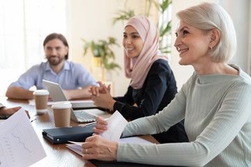 Smiling multiracial colleagues discuss ideas at office meeting