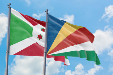 Seychelles and Burundi flags waving in the wind against white cloudy blue sky together. Diplomacy concept, international relations.