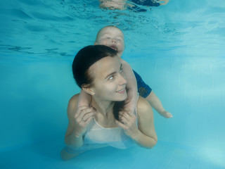 Mom with a little son dives underwater in a swimming pool