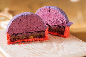 Sliced on half french mini mousse pastry dessert, closeup. Modern european portion cake with blueberry mousse