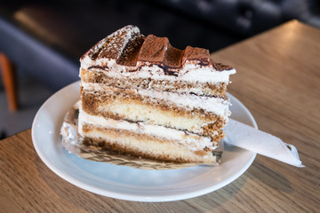 A piece of tiramisu cake on a white dish. Traditional italian dessert