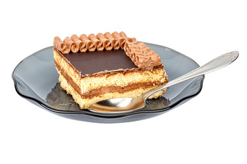 Quarter of shortbread cake with chocolate glaze and decorated by cream ornament on top on a saucer of dark smoky glass with tea spoon isolated on a white background