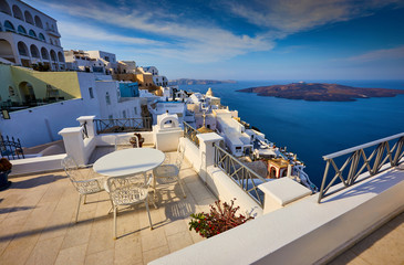 Fira town on Santorini island, Greece. Traditional and famous houses and churches with blue domes over the Caldera, Aegean sea. Terraces of Santorini hotels in the morning light.