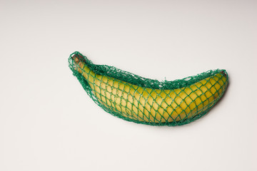 Single banana packed in net on white background