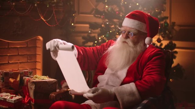 In a magical atmosphere Santa Claus reads a paper scroll with a list of children for gifts
