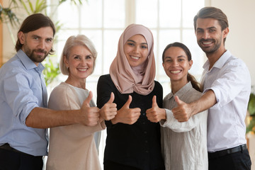Smiling multiethnic colleagues show thumbs up recommending service