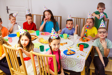 Frendly children celebrating birthday together. Kids eating pizza and enjoying party