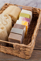 Basket with different handmade soap bars and loofah for body care