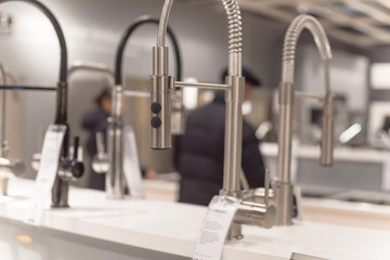 Blurry customer shopping for kitchen faucets at furniture showroom store in Texas, USA