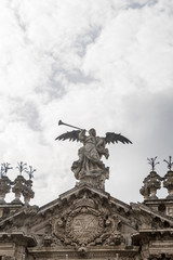 Angel playing the trumpet on the facade of the University of Seville with cloudy sky
