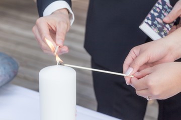 Wedding bride and groom couple burn candle at marriage ceremony. Elegant husband in dark suit and...