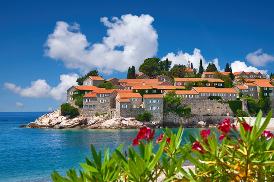 Amaizing view on the old town (city) on the Sveti Stefan Island. Small islet and resort in Montenegro. Balkans, Adriatic sea, Europe. Sunny day on the beach near the Saint Stefan island.