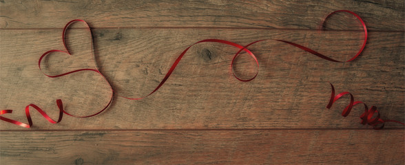 Heart shaped red ribbon on wood background , valentine background in vintage style
