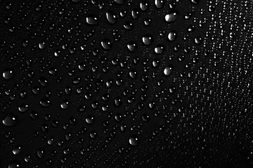 On a black background there are a lot of water drops of different sizes Black and white photo