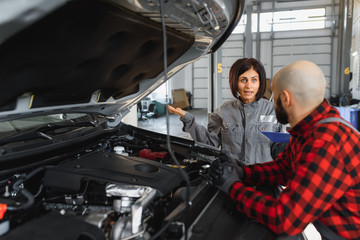 Male and female mechanics working on car
