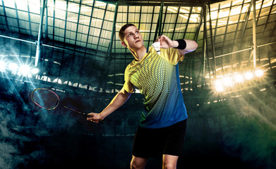Badminton player in sportswear with racket and shuttlecock on stadium. Olympic game. - obrazy, fototapety, plakaty