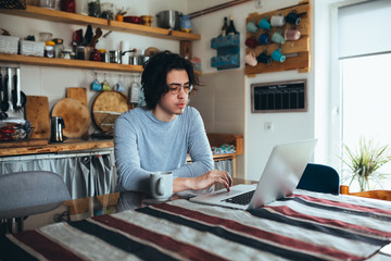 young man using laptops in kitchen, morning scene