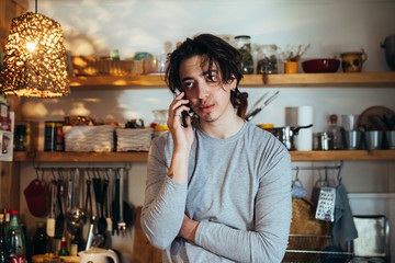 young man talking on mobile phone in his kitchen