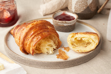 One delicious croissants on plate and hot drink in mug. Morning French breakfast