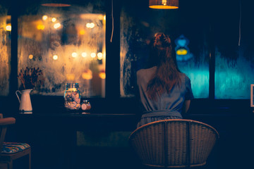 The only woman sitting in the coffee shop Lonely Facing outside on a rainy night with loneliness Picture tone dark style concept Loneliness on the night of love Valentine's Day